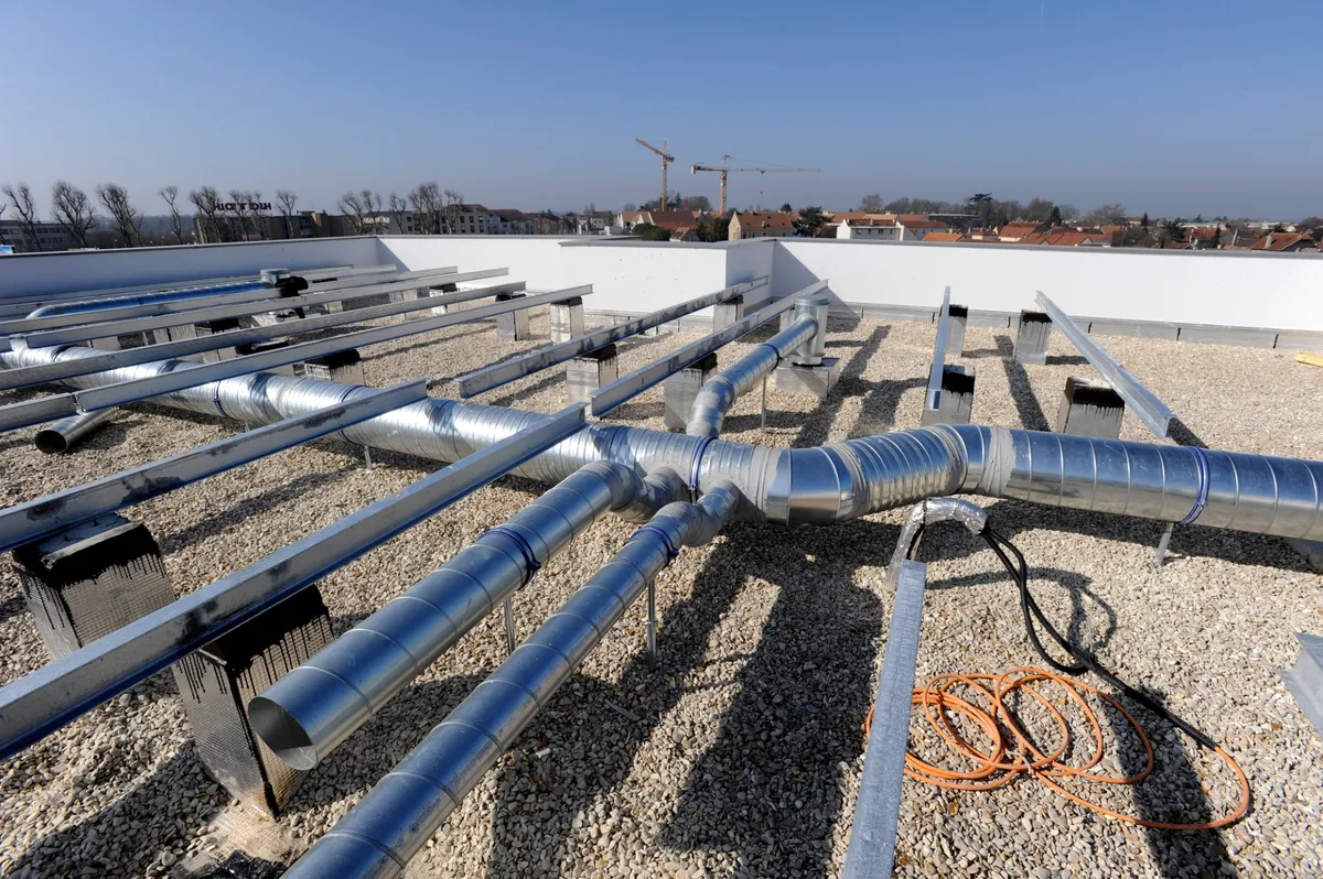 Installation de système de ventilation sur un toit plat pour améliorer la circulation de l'air dans un bâtiment professionnel.